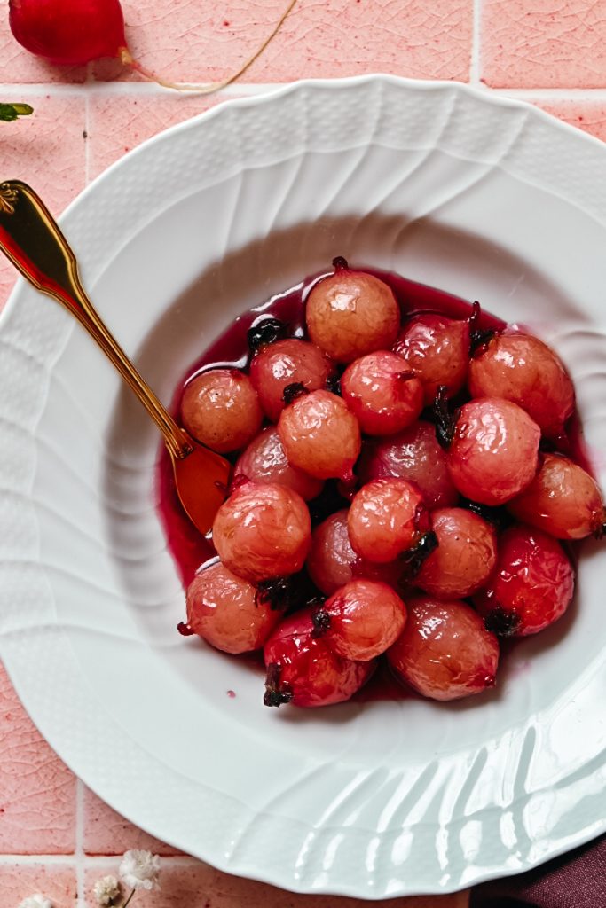 Glazed radishes in a white bowl with a fork.