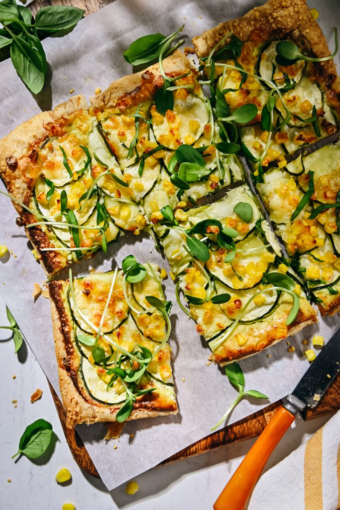 Overhead shot of sliced zucchini tart with microgreens on top.