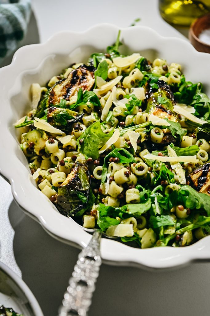 Side view of a zucchini pasta salad served in a white bowl.